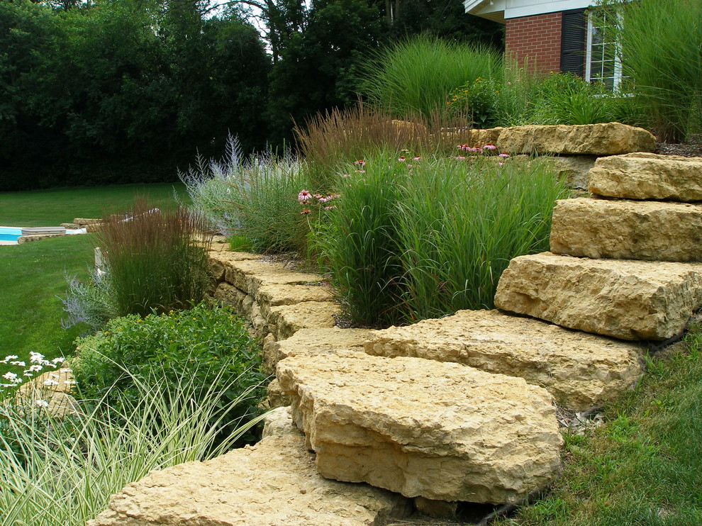 This is an example of a mid-sized transitional side yard garden in Chicago with a retaining wall and natural stone pavers.