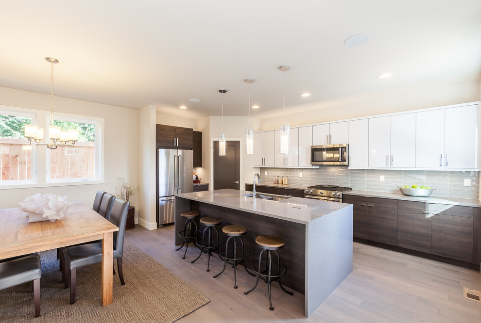 Large modern l-shaped eat-in kitchen in Seattle with an undermount sink, flat-panel cabinets, white cabinets, grey splashback, glass tile splashback, stainless steel appliances, vinyl floors, with island and terrazzo benchtops.