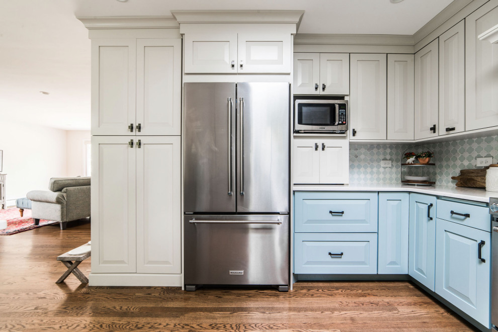 Inspiration for a mid-sized transitional u-shaped medium tone wood floor and brown floor eat-in kitchen remodel in Chicago with a farmhouse sink, raised-panel cabinets, blue cabinets, quartz countertops, white backsplash, glass tile backsplash, stainless steel appliances, no island and white countertops