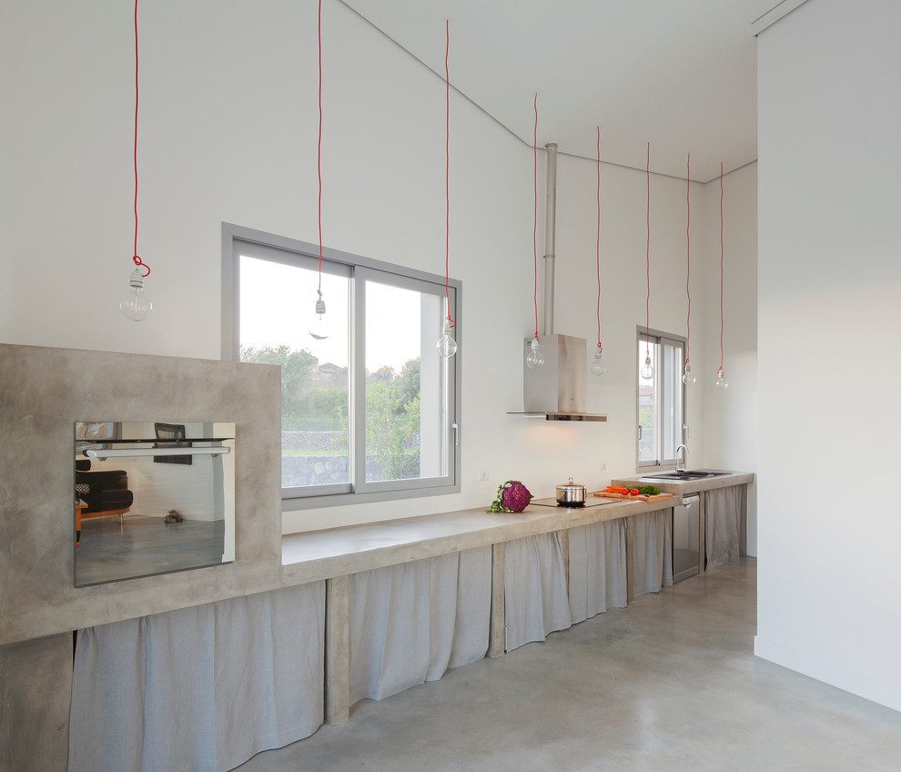 This is an example of a contemporary single-wall open plan kitchen in Catania-Palermo with open cabinets, grey cabinets, concrete benchtops, stainless steel appliances and concrete floors.