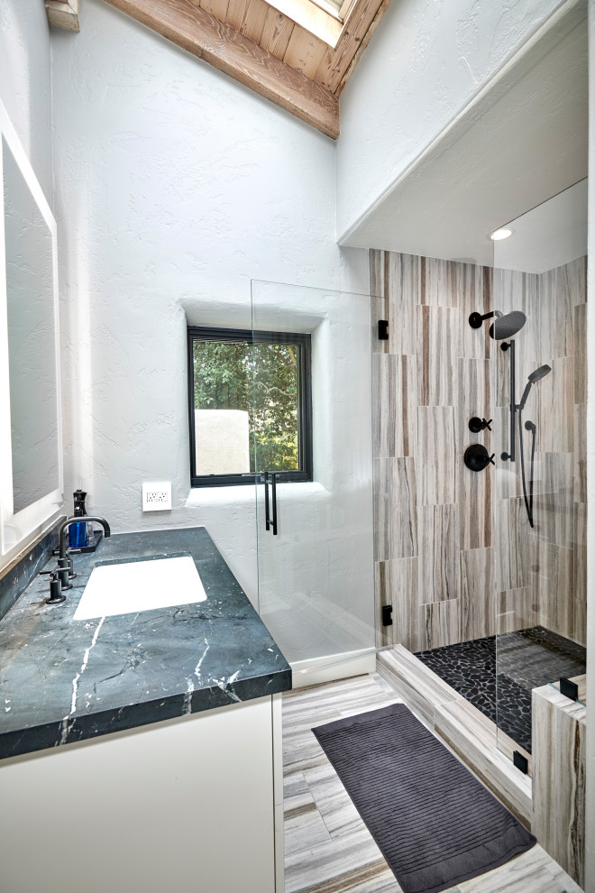 Photo of a medium sized classic ensuite bathroom in San Diego with recessed-panel cabinets, white cabinets, a freestanding bath, a walk-in shower, a two-piece toilet, white tiles, marble tiles, white walls, marble flooring, a submerged sink, quartz worktops, white floors, a hinged door, black worktops, a wall niche, a single sink, a built in vanity unit and exposed beams.