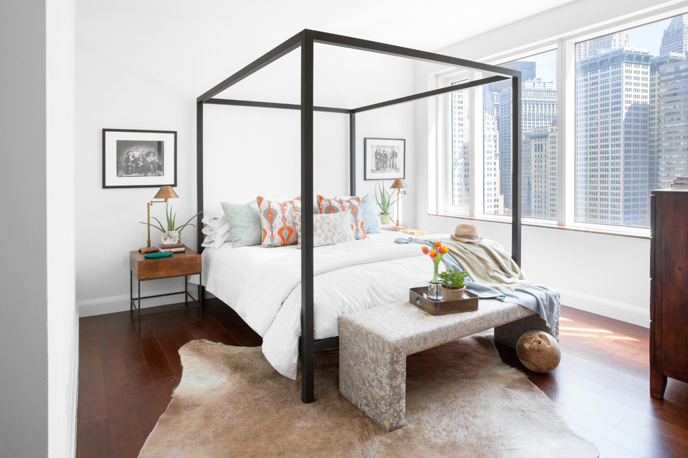 This is an example of a contemporary master bedroom in New York with white walls and dark hardwood floors.