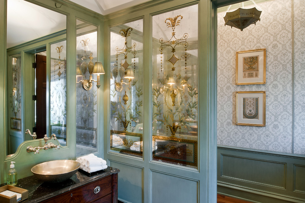 Mid-sized traditional powder room in New York with furniture-like cabinets, green walls, a vessel sink, granite benchtops, dark wood cabinets and black benchtops.