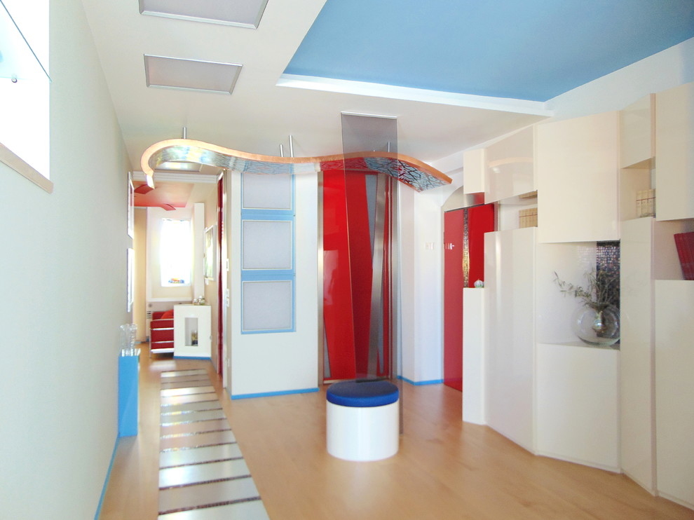 This is an example of a mid-sized modern foyer in Other with multi-coloured walls, light hardwood floors, a single front door, a red front door and brown floor.