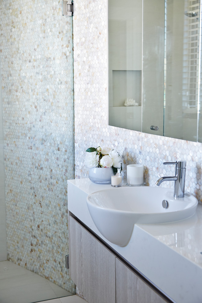 Traditional powder room in Sydney with flat-panel cabinets, light wood cabinets, multi-coloured tile, mosaic tile, white walls, porcelain floors, an integrated sink and solid surface benchtops.