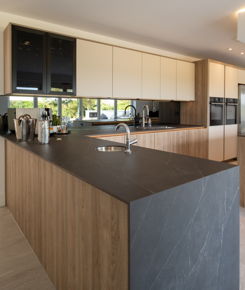Inspiration for a large contemporary l-shaped open plan kitchen in Hampshire with flat-panel cabinets, white cabinets, grey splashback, glass sheet splashback, porcelain floors, with island, multi-coloured floor and grey benchtop.
