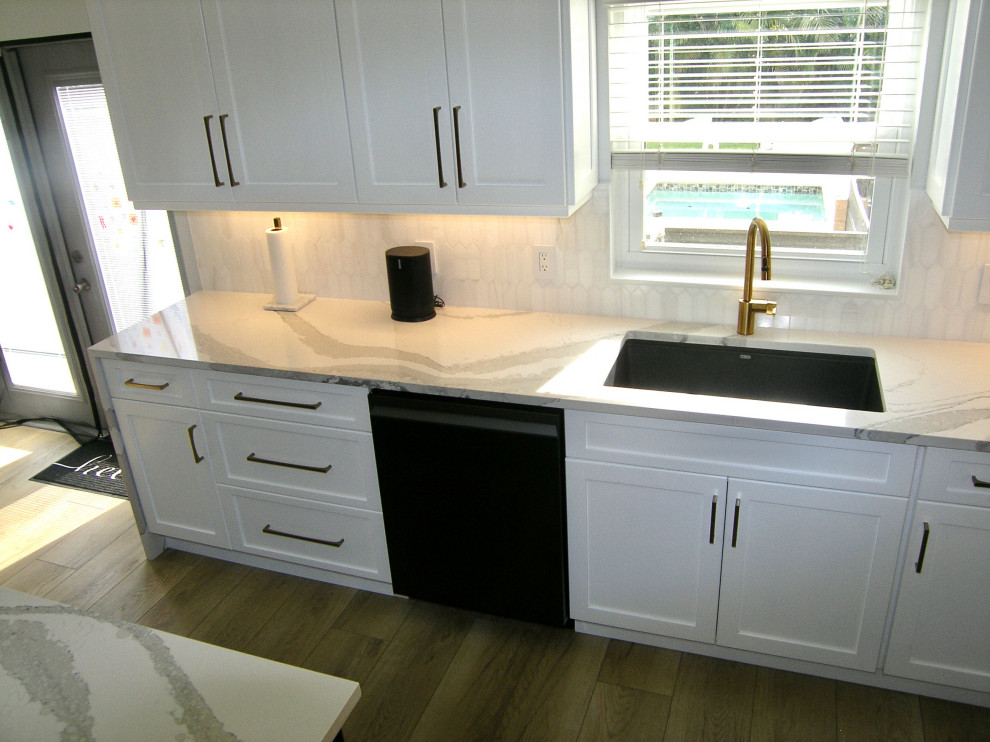 Design ideas for a large u-shaped eat-in kitchen in Tampa with an undermount sink, shaker cabinets, white cabinets, quartz benchtops, white splashback, ceramic splashback, black appliances, with island and grey benchtop.