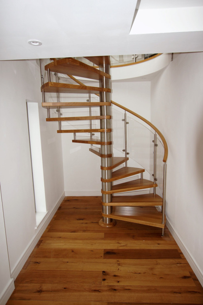 Idée de décoration pour un escalier hélicoïdal minimaliste de taille moyenne avec des marches en bois, des contremarches en verre et un garde-corps en verre.