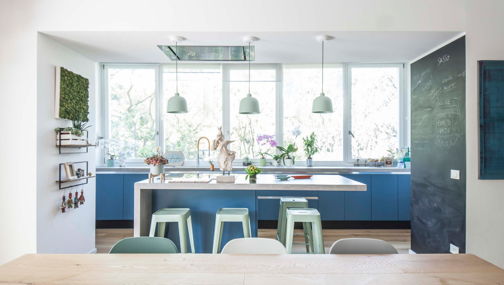Inspiration for a mid-sized contemporary single-wall open plan kitchen in Rome with an integrated sink, beaded inset cabinets, turquoise cabinets, concrete benchtops, panelled appliances, medium hardwood floors, with island, beige floor and grey benchtop.