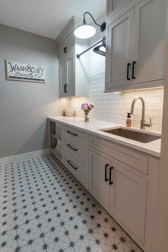 Large modern laundry room in Milwaukee with recessed-panel cabinets, light wood cabinets, white walls, ceramic floors, grey floor and planked wall panelling.