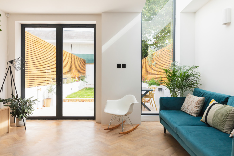 Idee per un soggiorno contemporaneo aperto con pareti bianche, pavimento in legno massello medio e TV a parete