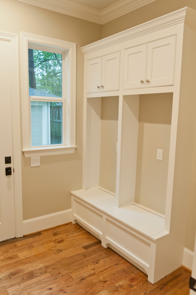 Mid-sized traditional single-wall utility room in Houston with recessed-panel cabinets, white cabinets and medium hardwood floors.