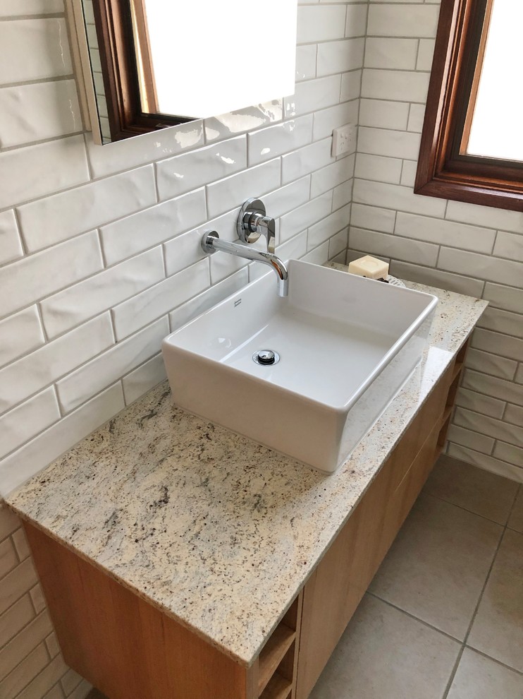 Mid-sized contemporary master bathroom in Other with furniture-like cabinets, light wood cabinets, an open shower, a one-piece toilet, white tile, ceramic tile, white walls, ceramic floors, a vessel sink, granite benchtops, beige floor, an open shower and multi-coloured benchtops.