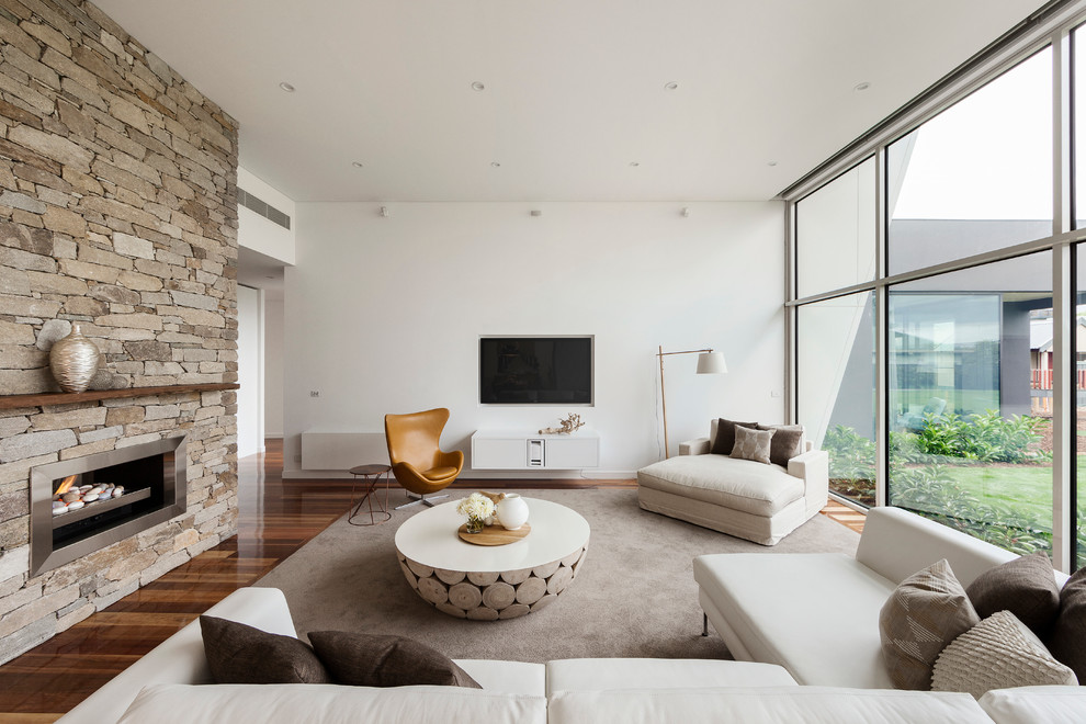 This is an example of a contemporary formal living room in Melbourne with white walls, medium hardwood floors and a wall-mounted tv.