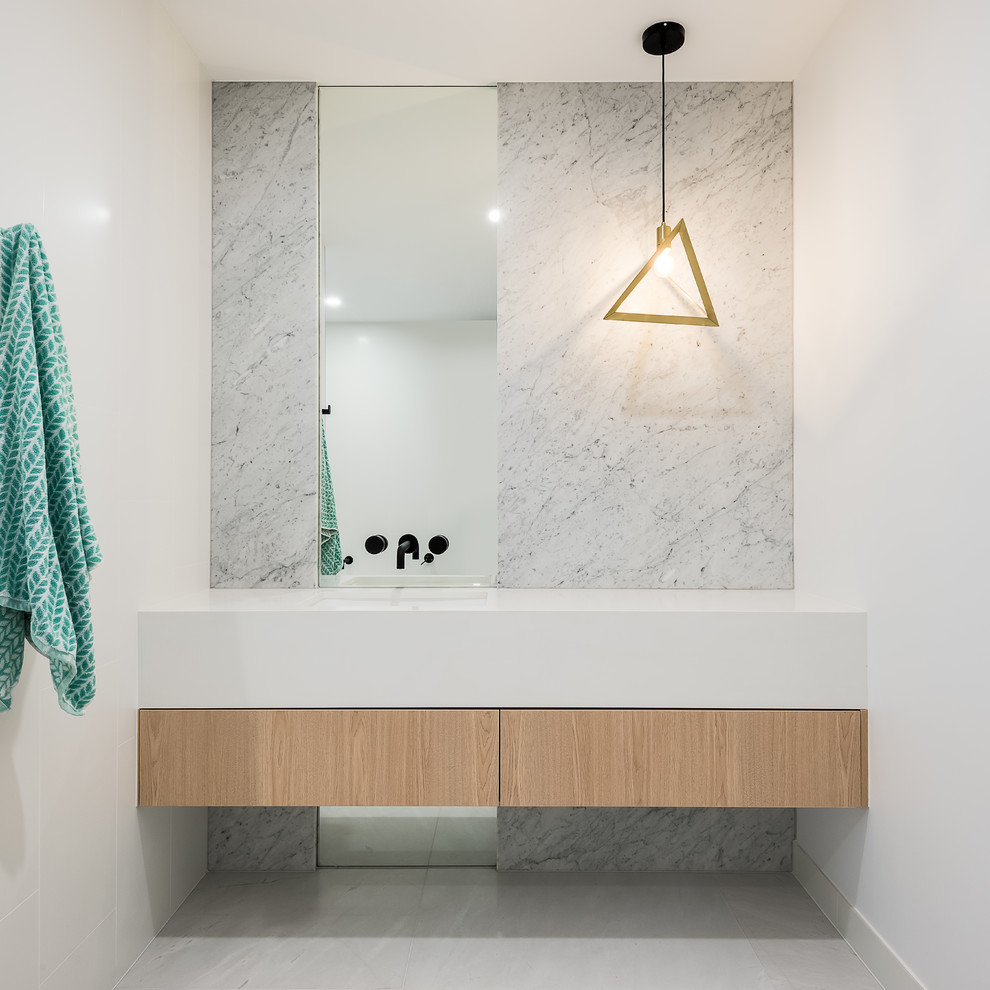 Photo of a mid-sized modern bathroom in Brisbane with light wood cabinets, a freestanding tub, white tile, gray tile, marble, marble floors, quartzite benchtops, an open shower, white benchtops, flat-panel cabinets, white walls, an integrated sink and grey floor.