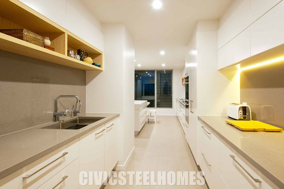 Photo of a mid-sized contemporary galley eat-in kitchen with an undermount sink, white cabinets, quartz benchtops, stainless steel appliances, porcelain floors and with island.