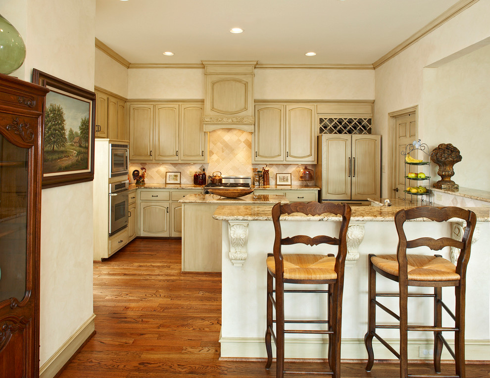 This is an example of a large traditional u-shaped kitchen in Dallas with raised-panel cabinets, beige cabinets, beige splashback, panelled appliances, dark hardwood floors, ceramic splashback, with island and brown floor.