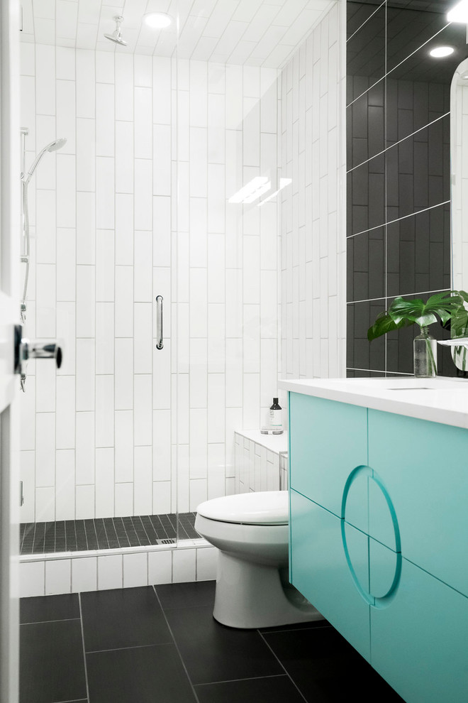 Photo of a mid-sized midcentury 3/4 bathroom in Calgary with furniture-like cabinets, turquoise cabinets, black tile, porcelain tile, beige walls, porcelain floors, an undermount sink, quartzite benchtops, grey floor, a hinged shower door, an alcove shower, a one-piece toilet and white benchtops.