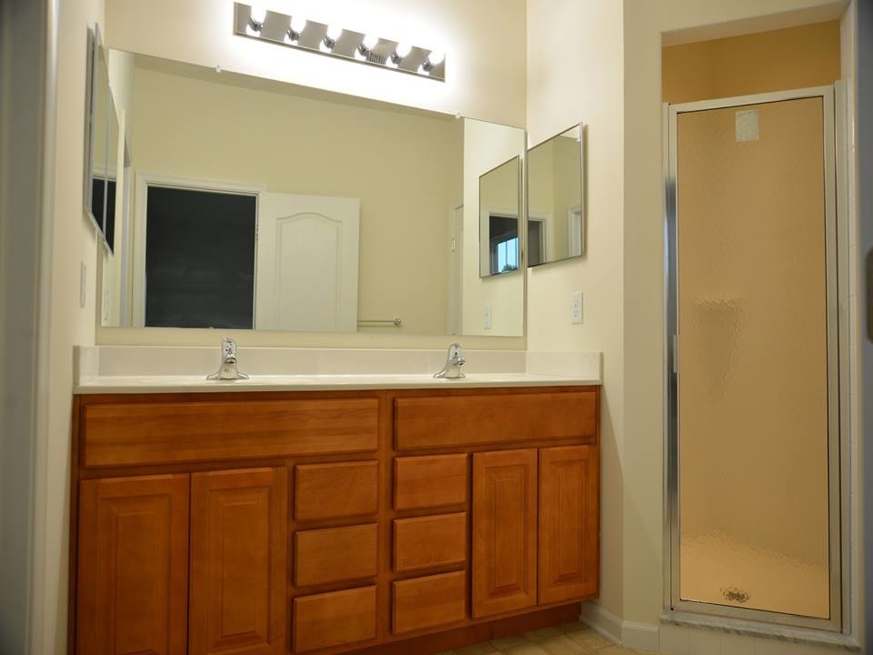 Inspiration for a mid-sized master corner shower remodel in Philadelphia with medium tone wood cabinets, solid surface countertops and white walls