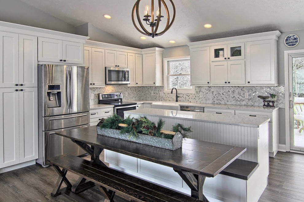 Eat-in kitchen - mid-sized transitional l-shaped vinyl floor eat-in kitchen idea with a farmhouse sink, shaker cabinets, white cabinets, quartz countertops, white backsplash, stone tile backsplash, stainless steel appliances and an island