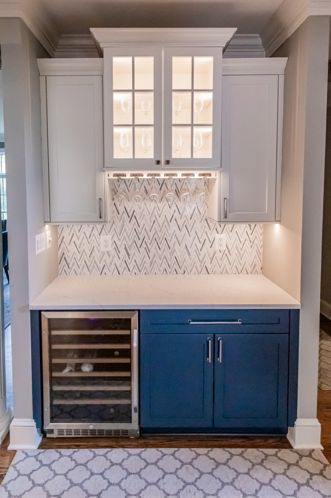 Large transitional u-shaped medium tone wood floor and brown floor eat-in kitchen photo in Baltimore with a farmhouse sink, shaker cabinets, blue cabinets, quartz countertops, white backsplash, marble backsplash, stainless steel appliances, an island and white countertops