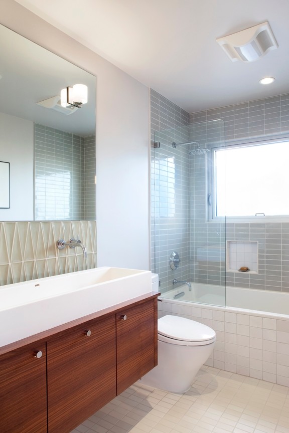 This is an example of a small midcentury master bathroom in San Francisco with a vessel sink, flat-panel cabinets, medium wood cabinets, wood benchtops, a drop-in tub, a shower/bathtub combo, a one-piece toilet, gray tile, ceramic tile, white walls, ceramic floors, white floor and an open shower.