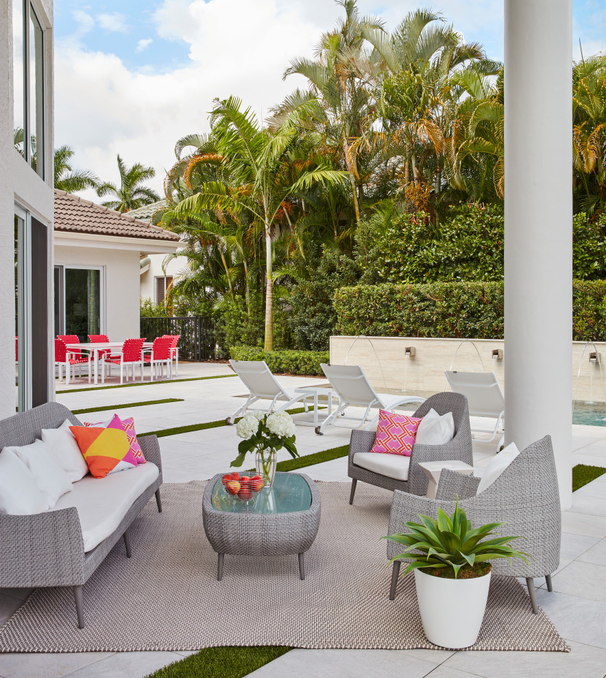 Photo of a contemporary backyard patio in Miami with tile and a roof extension.
