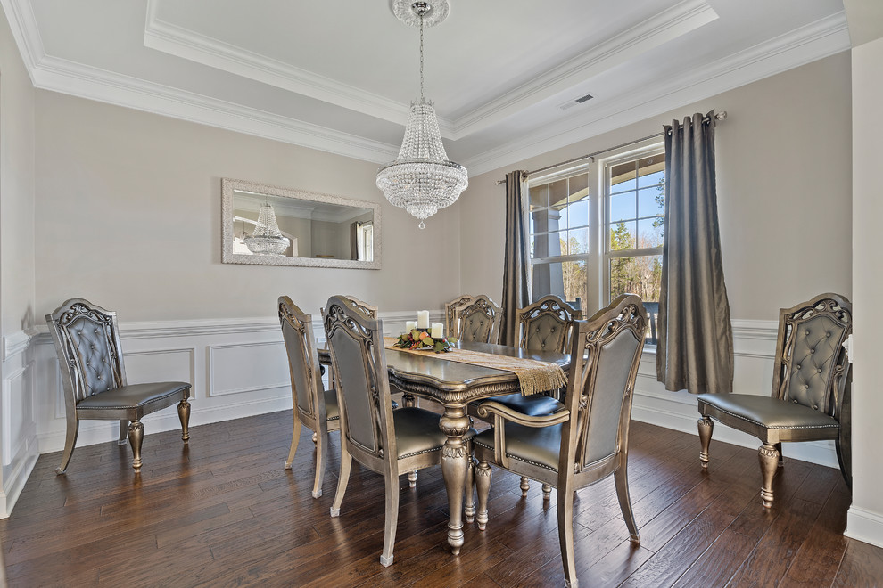 This is an example of a traditional dining room in Charlotte with beige walls, dark hardwood floors and brown floor.