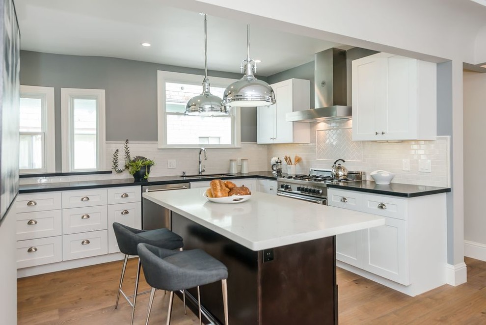 Photo of a large traditional u-shaped eat-in kitchen in San Francisco with a single-bowl sink, shaker cabinets, yellow cabinets, quartz benchtops, white splashback, ceramic splashback, stainless steel appliances, medium hardwood floors and with island.