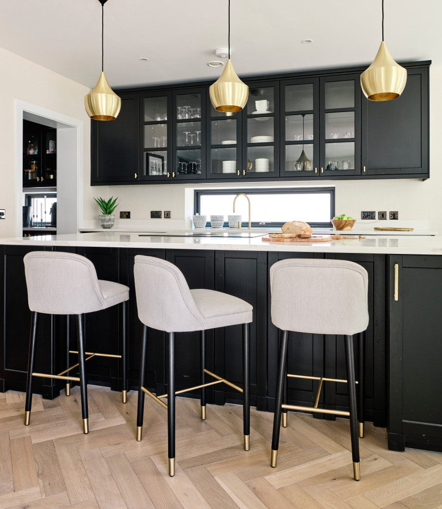 Foto di una grande cucina design con lavello integrato, ante in stile shaker, ante nere, top in quarzite, paraspruzzi bianco, elettrodomestici da incasso, pavimento in laminato, pavimento beige e top bianco