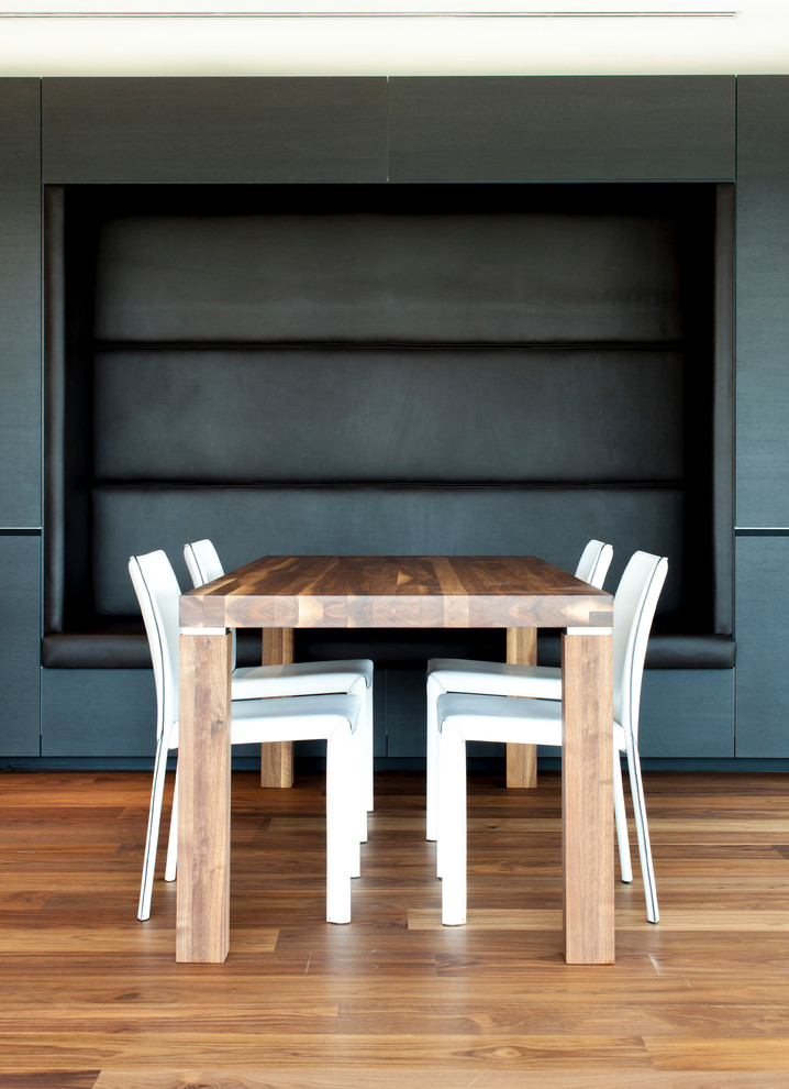 Foto di una grande sala da pranzo aperta verso la cucina contemporanea con pareti nere e pavimento in legno massello medio
