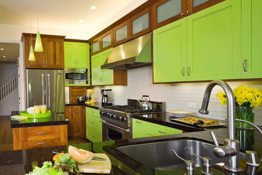 Photo of a mid-sized arts and crafts u-shaped eat-in kitchen in Minneapolis with flat-panel cabinets, green cabinets, with island, an undermount sink, white splashback, matchstick tile splashback, stainless steel appliances, light hardwood floors, brown floor and black benchtop.