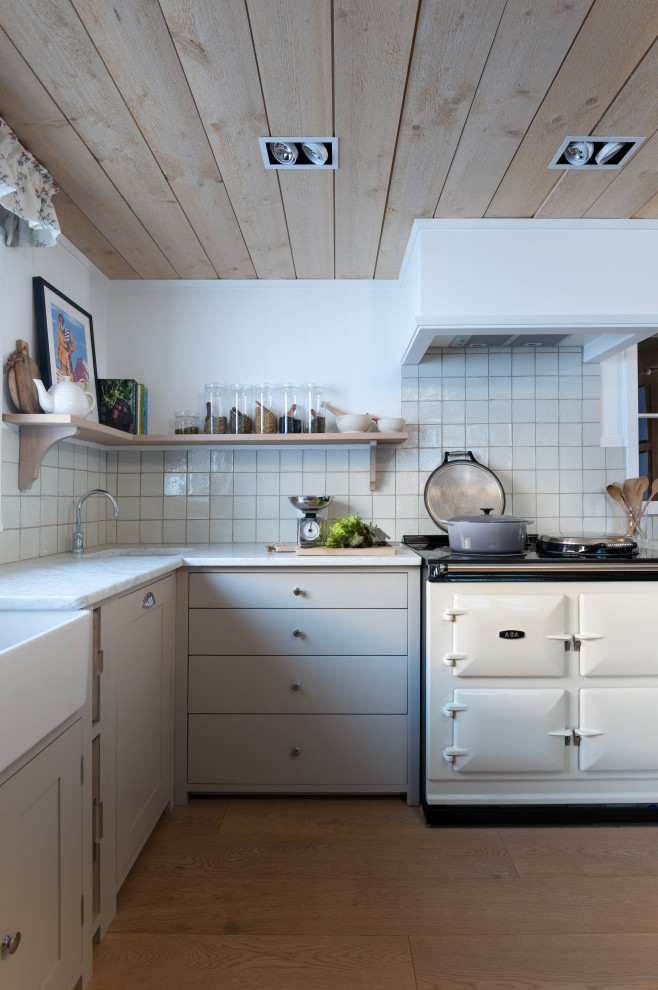 Inspiration for a country kitchen in Other with a drop-in sink, recessed-panel cabinets, grey cabinets, marble benchtops, grey splashback, ceramic splashback, coloured appliances, light hardwood floors, a peninsula, brown floor, white benchtop and wood.