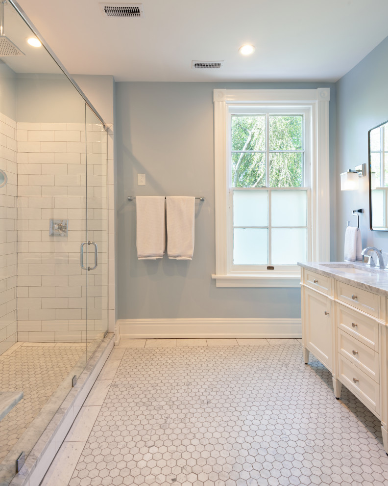 Photo of a mid-sized traditional master bathroom in Richmond with recessed-panel cabinets, white cabinets, an alcove shower, a two-piece toilet, white tile, ceramic tile, blue walls, marble floors, an undermount sink, marble benchtops, grey floor, a hinged shower door, grey benchtops, a double vanity and a freestanding vanity.