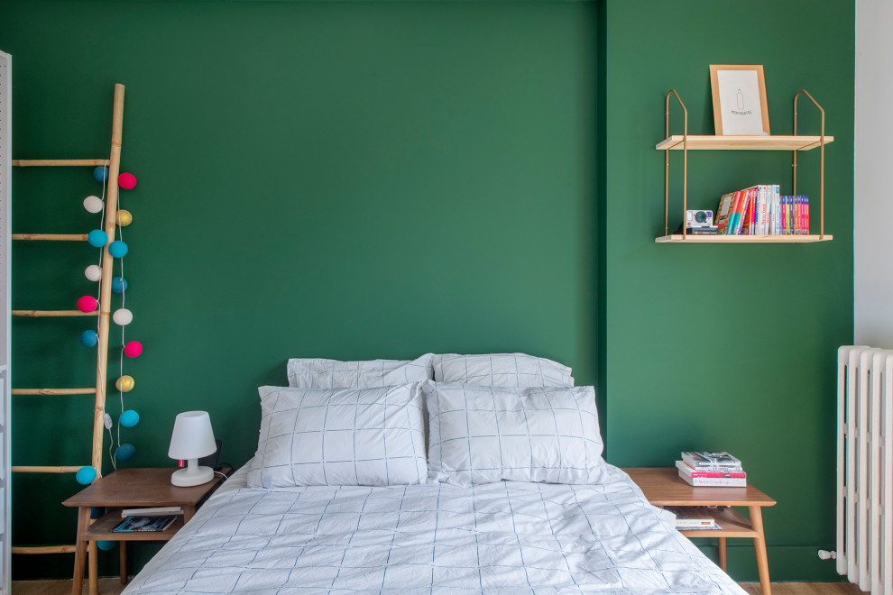 This is an example of a small scandinavian master bedroom in Paris with green walls, light hardwood floors and beige floor.