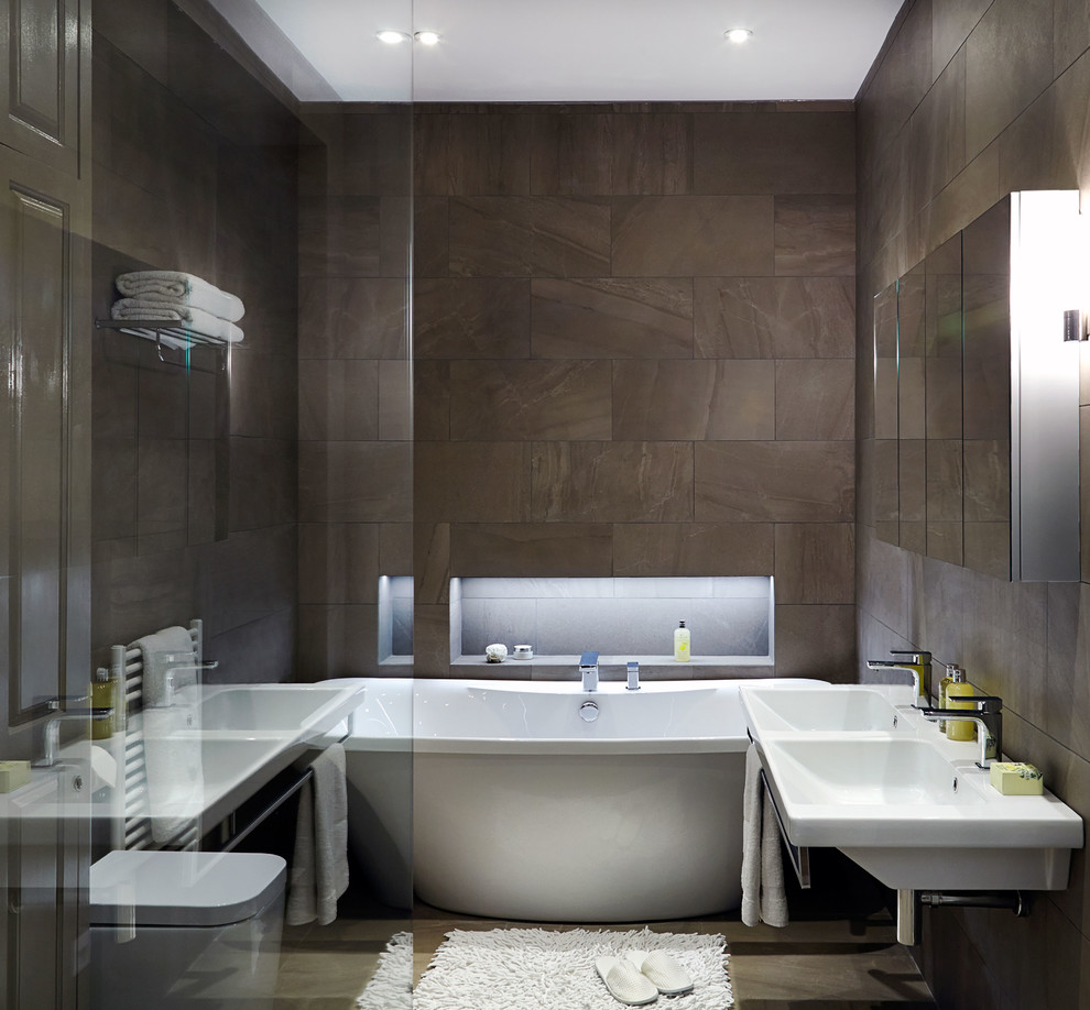 Contemporary bathroom in London with a wall-mount sink, a freestanding tub and brown walls.