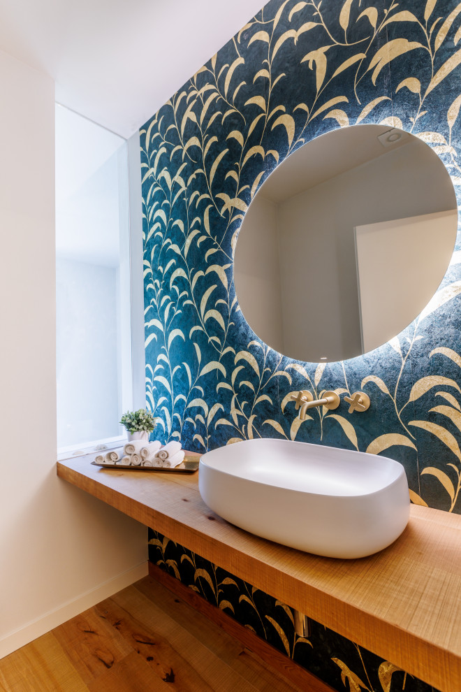 Cette image montre un petit WC et toilettes design en bois clair avec un plan de toilette en bois, meuble-lavabo suspendu, un mur vert, parquet peint et du papier peint.