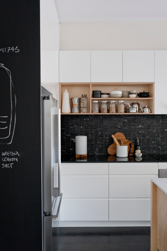Scandinavian kitchen in Sydney with flat-panel cabinets, black splashback and black floor.
