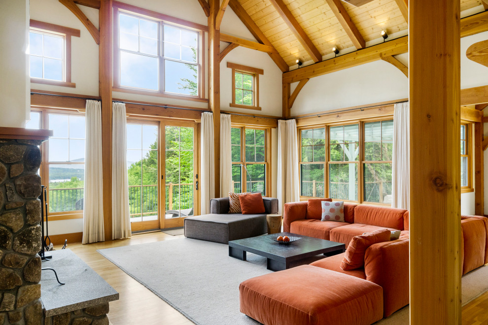 This is an example of an expansive arts and crafts open concept living room in Other with white walls, medium hardwood floors, a standard fireplace, a stone fireplace surround and exposed beam.