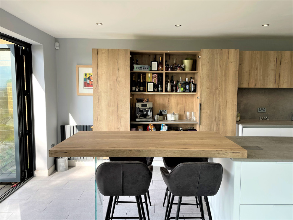 Design ideas for a mid-sized contemporary l-shaped eat-in kitchen in Other with a single-bowl sink, flat-panel cabinets, white cabinets, solid surface benchtops, grey splashback, vinyl floors, with island, grey floor and grey benchtop.
