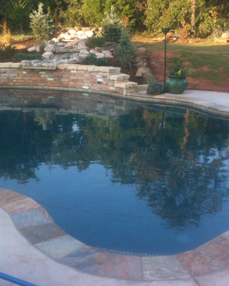 Design ideas for a large traditional backyard custom-shaped pool in Oklahoma City with tile.