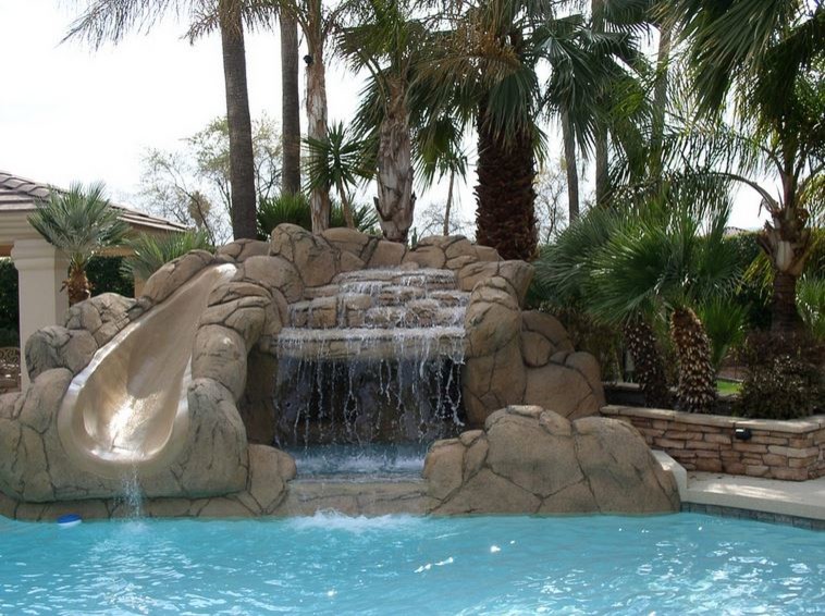 Design ideas for a mid-sized traditional backyard custom-shaped natural pool in Phoenix with a water slide and stamped concrete.