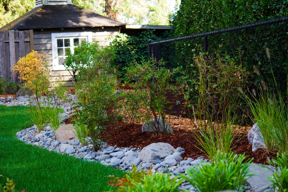 Inspiration for a backyard river rock and metal fence landscaping in Portland.