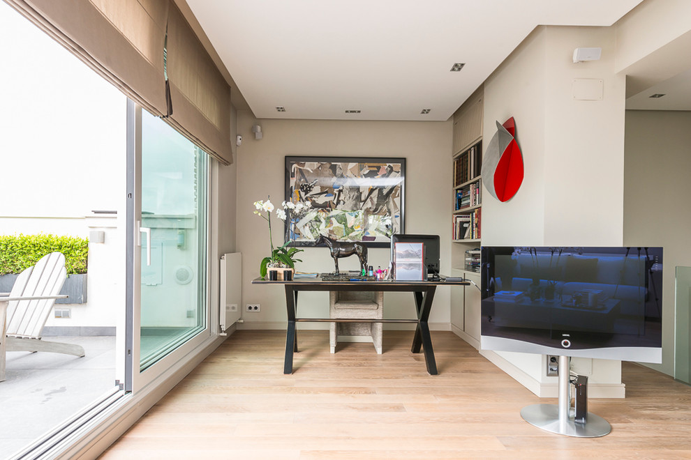 This is an example of a mid-sized transitional study room in Madrid with beige walls, light hardwood floors, no fireplace and a freestanding desk.