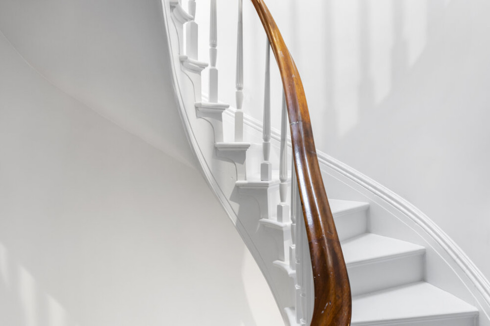 Imagen de escalera curva clásica renovada extra grande con escalones de madera pintada, contrahuellas de madera pintada y barandilla de madera