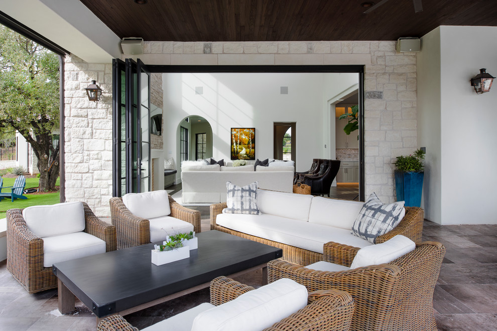 Large mediterranean backyard patio in Austin with a roof extension, with fireplace and concrete pavers.