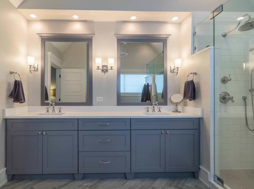 Large country master bathroom in Chicago with shaker cabinets, blue cabinets, an alcove shower, a one-piece toilet, white tile, limestone, limestone floors, an integrated sink, solid surface benchtops, blue floor, a sliding shower screen, white benchtops, a shower seat, a single vanity, a freestanding vanity, wallpaper, wallpaper and white walls.