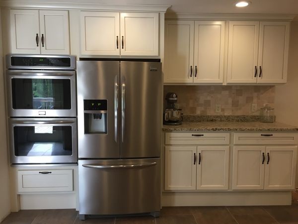Enclosed kitchen - small transitional l-shaped brown floor and porcelain tile enclosed kitchen idea with a double-bowl sink, shaker cabinets, white cabinets, granite countertops, beige backsplash, stone tile backsplash, stainless steel appliances, no island and gray countertops
