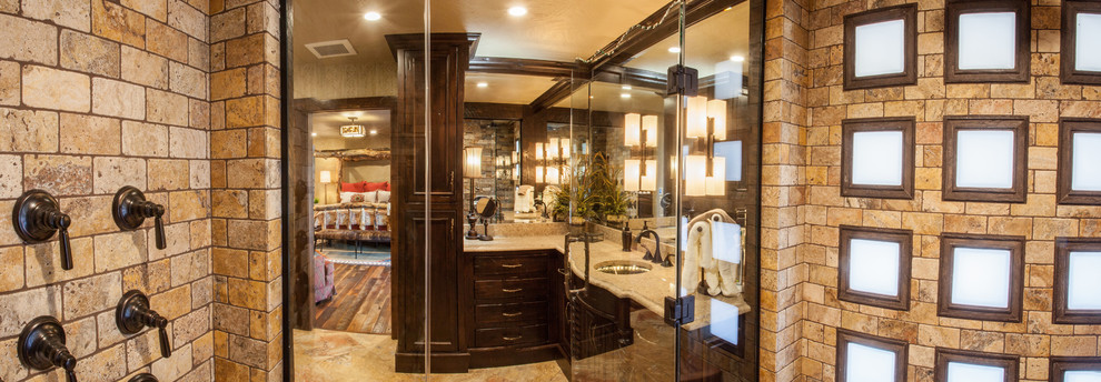 Example of a mid-sized mountain style master beige tile and stone tile travertine floor walk-in shower design with recessed-panel cabinets, dark wood cabinets, a two-piece toilet, beige walls, an undermount sink and quartz countertops