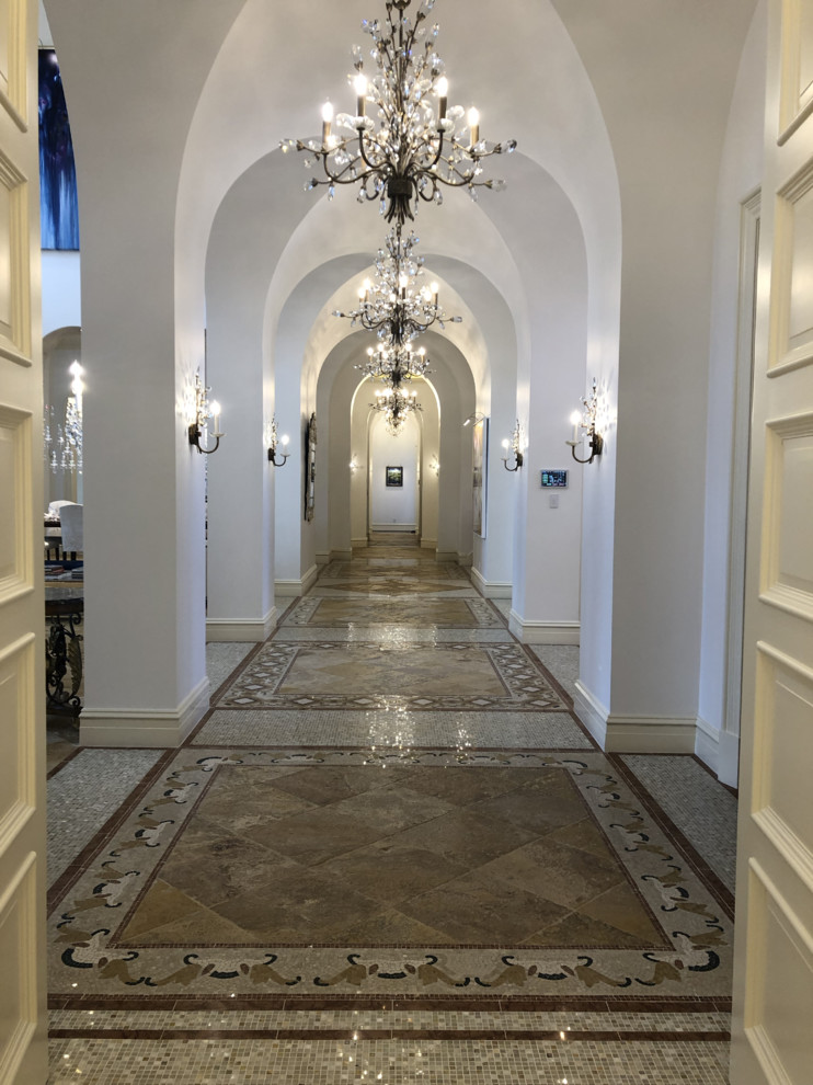 This is an example of an expansive traditional hallway in Miami with white walls, marble floors and brown floor.